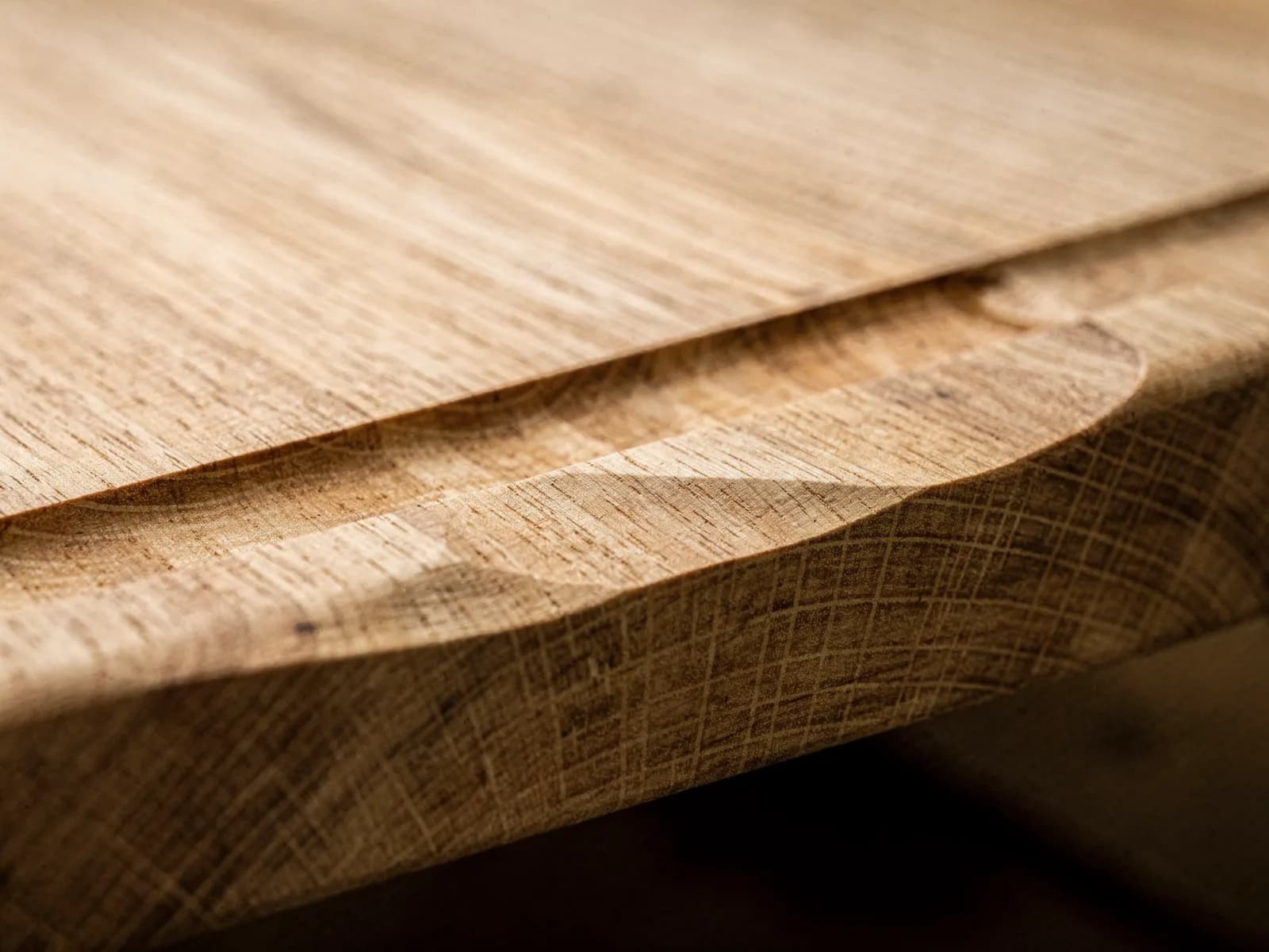 Close-up of the routed juice groove and quartersawn grain at the end of a thick white oak board